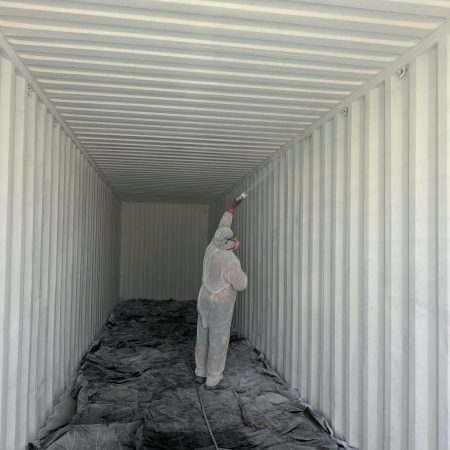 Worker applying a coating inside a corrugated metal container